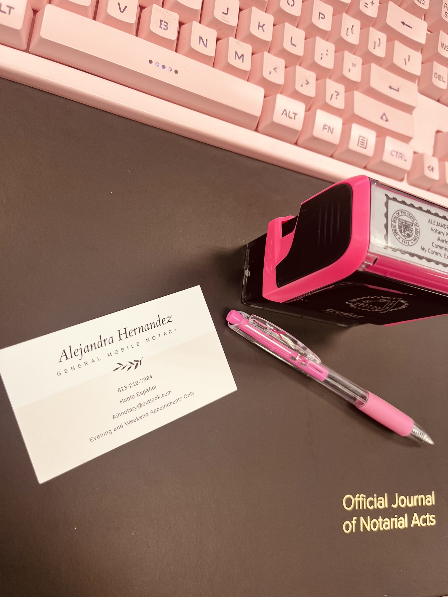 PHoto shows keyboard, pen, Notary stamp and a business card with the name Alejandra Hernandez on it.