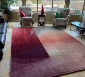 Photo shows a living with a red rug. The left side is beautiful an clean while the right side is dusty and dull. It shows a before and after using J & M Cleaning for cleaning carpet.
