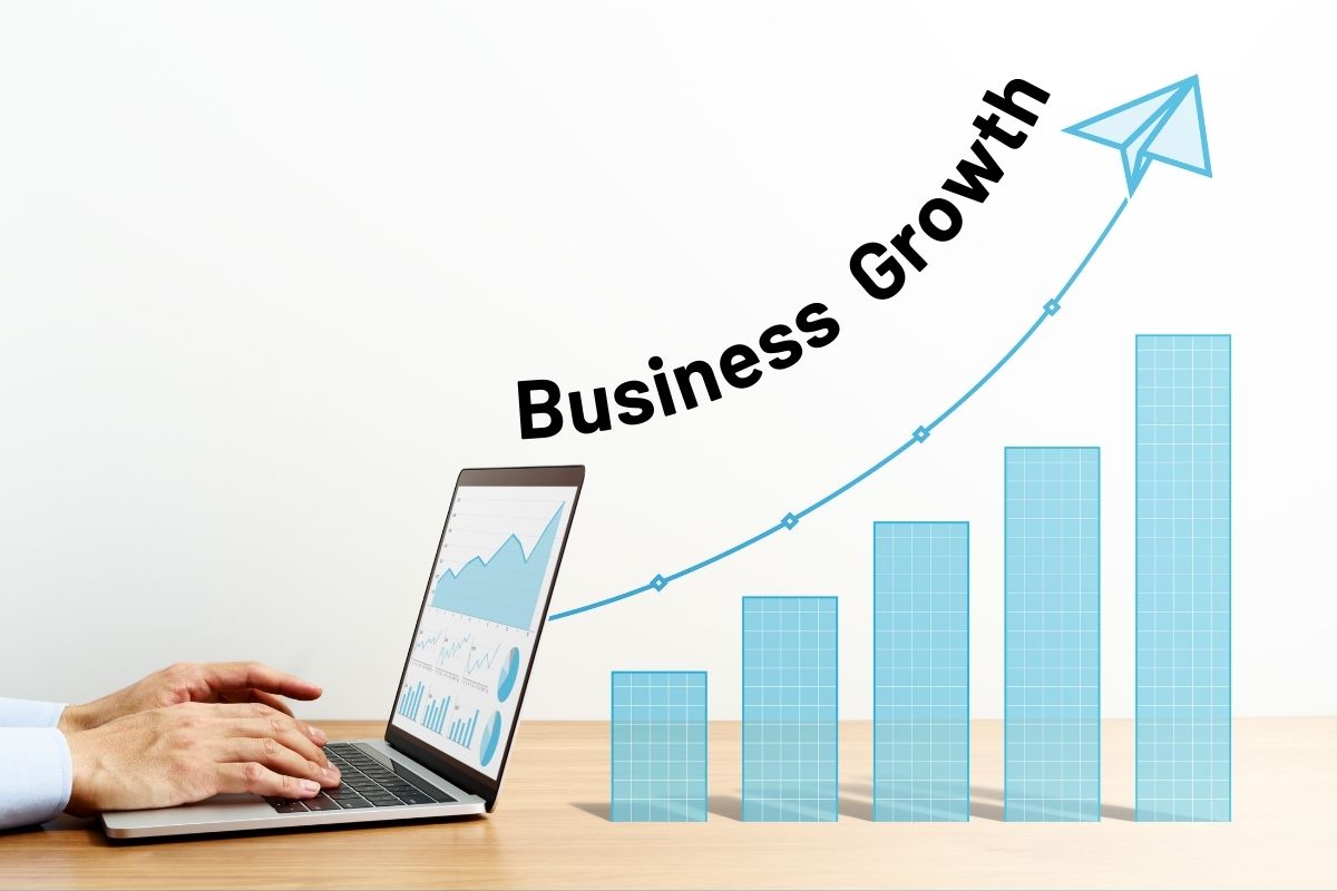 Photo shows a laptop on a desk with a bar chart indicating growth to the right. Works "Business Growth" follow curve of growth line.
